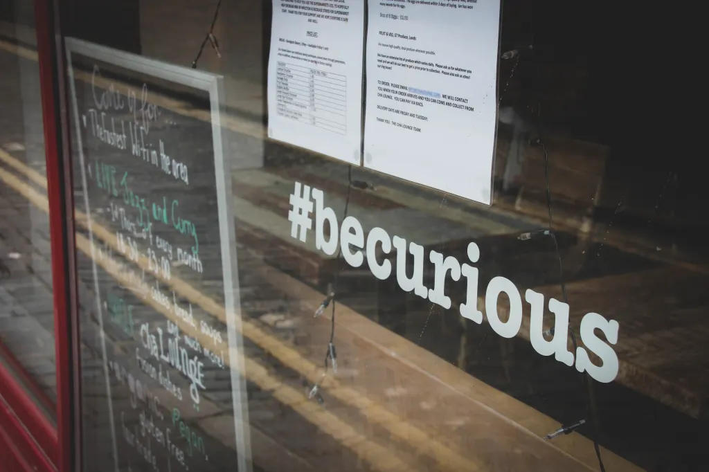 Photo of shop window with a sign saying #becurious