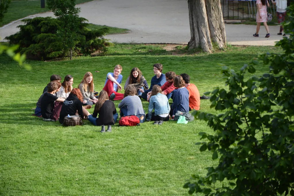 Photo of circle of young people on the grass talking.